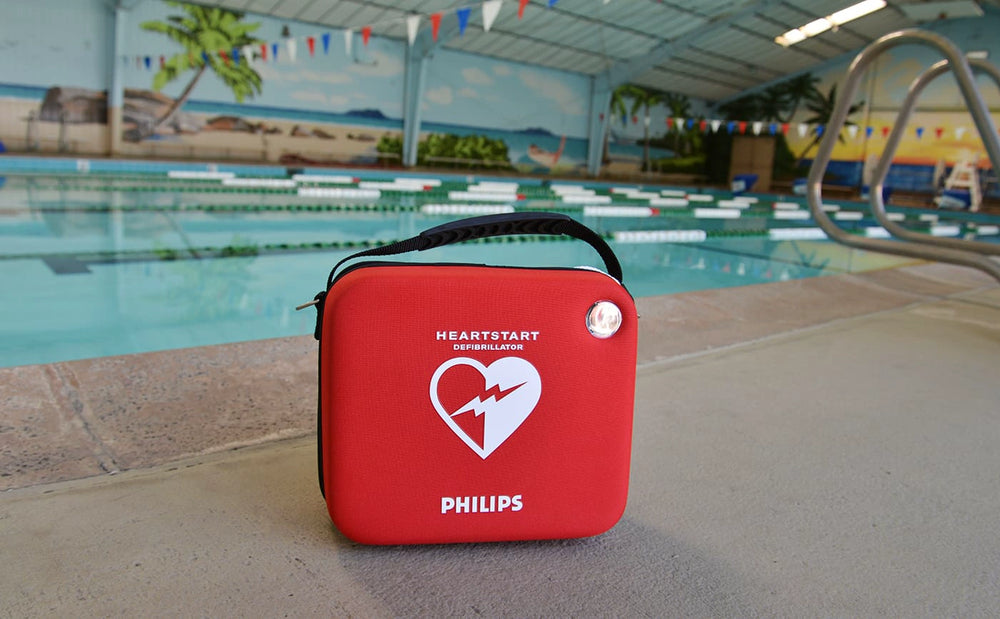 Red Philips HeartStart AED case sitting poolside at an indoor swimming pool