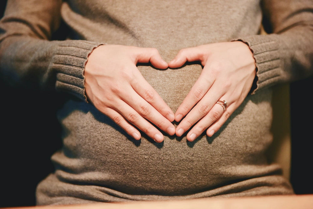 Pregnant woman's hands forming a heart shape over her belly