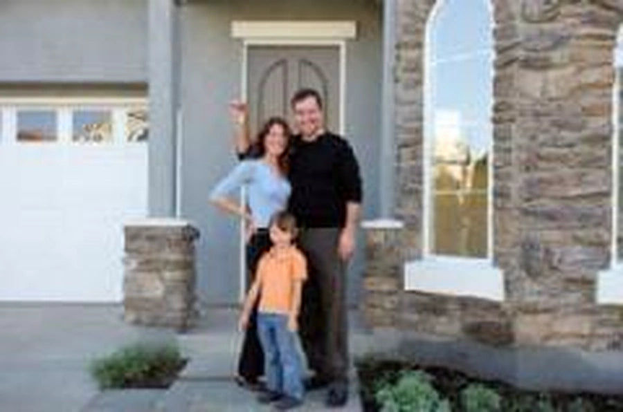 Family of three standing in front of their house