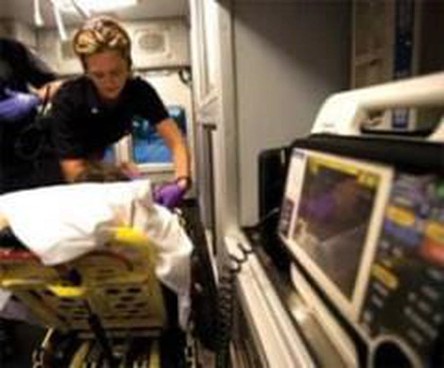 EMS responder attending to a patient in an ambulance with a cardiac monitor visible