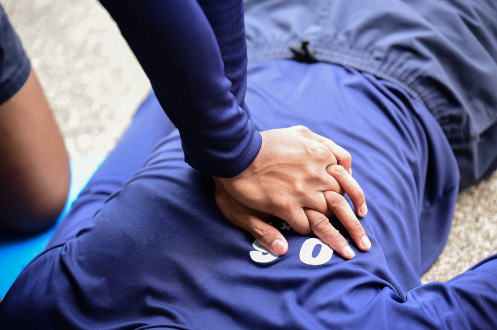 Rescuer's hands positioned for chest compressions on a person lying on the ground