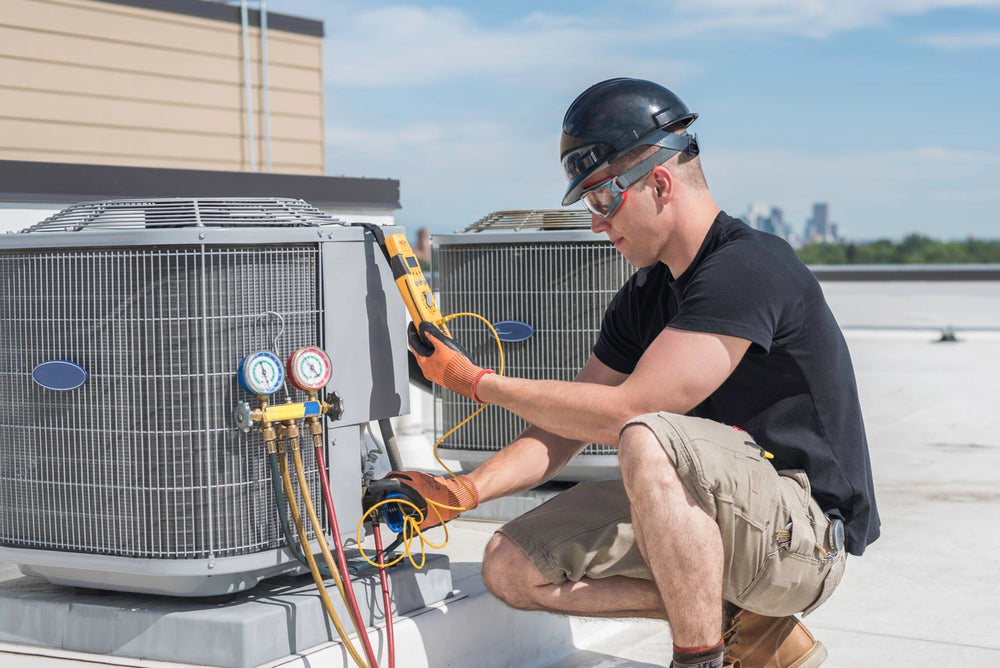 HVAC technician on a rooftop using pressure gauges and a digital meter on an air conditioning unit
