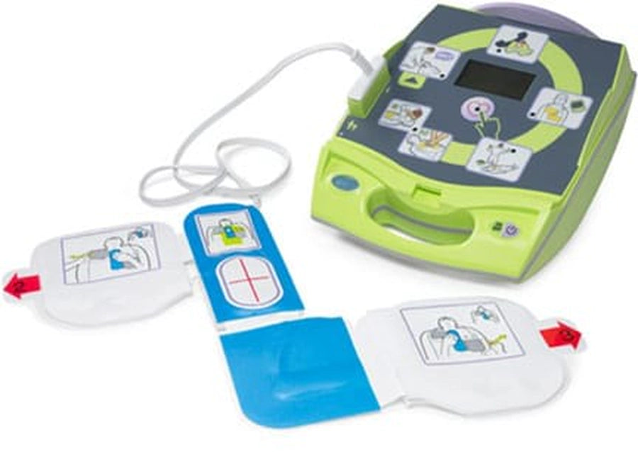 Green ZOLL AED device with electrode pads and connector cable laid out beside it
