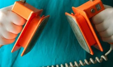person holding defibrillator paddles