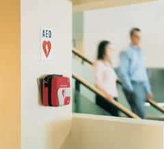 man and woman walking past aed at office