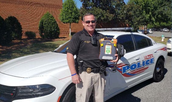 man with aed in front of patrol car