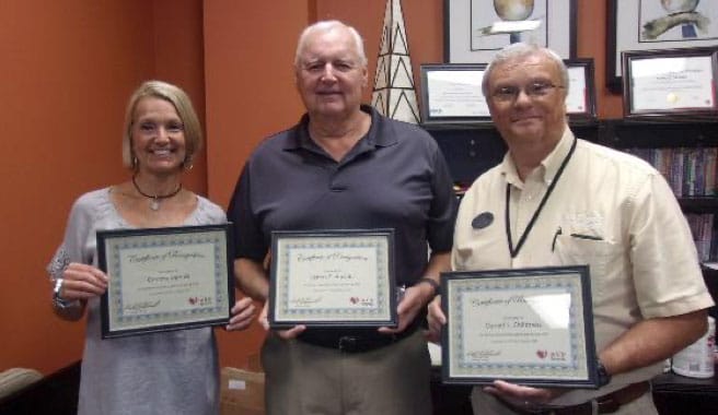 three people with certificates of recognition